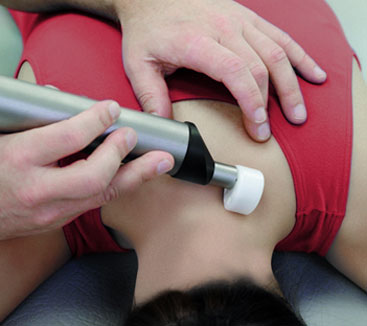 Physiotherapist applying Matrix Rhythm Therapy device to a patient’s shoulder area to relieve muscle tension and improve circulation.