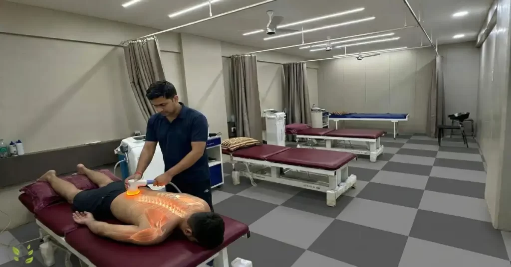 A physiotherapist applying TECAR therapy radiofrequency device to a patient's lower back for deep tissue healing and pain relief in a clinic setting.
